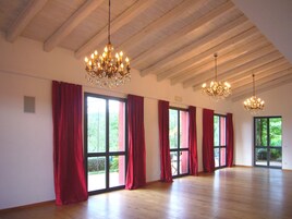 Amplia habitación con ventanas grandes, pisos de madera y dos candelabros.