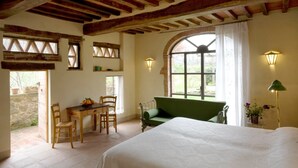 Une chambre à coucher avec un lit, un canapé vert, une table en bois avec des chaises et une fenêtre avec des rideaux.