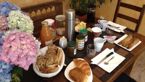A breakfast table with bread, pastries, and condiments. - Loargann Chambres d'Hotes (Plogastel-Saint-Germain)