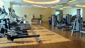 Een fitnessruimte met loopbanden, elliptische trainers en gewichten.