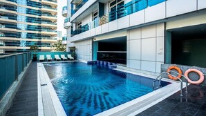Een modern overdekt zwembad met helderblauw water, omgeven door een betegeld zonnedek en een glazen balustrade.