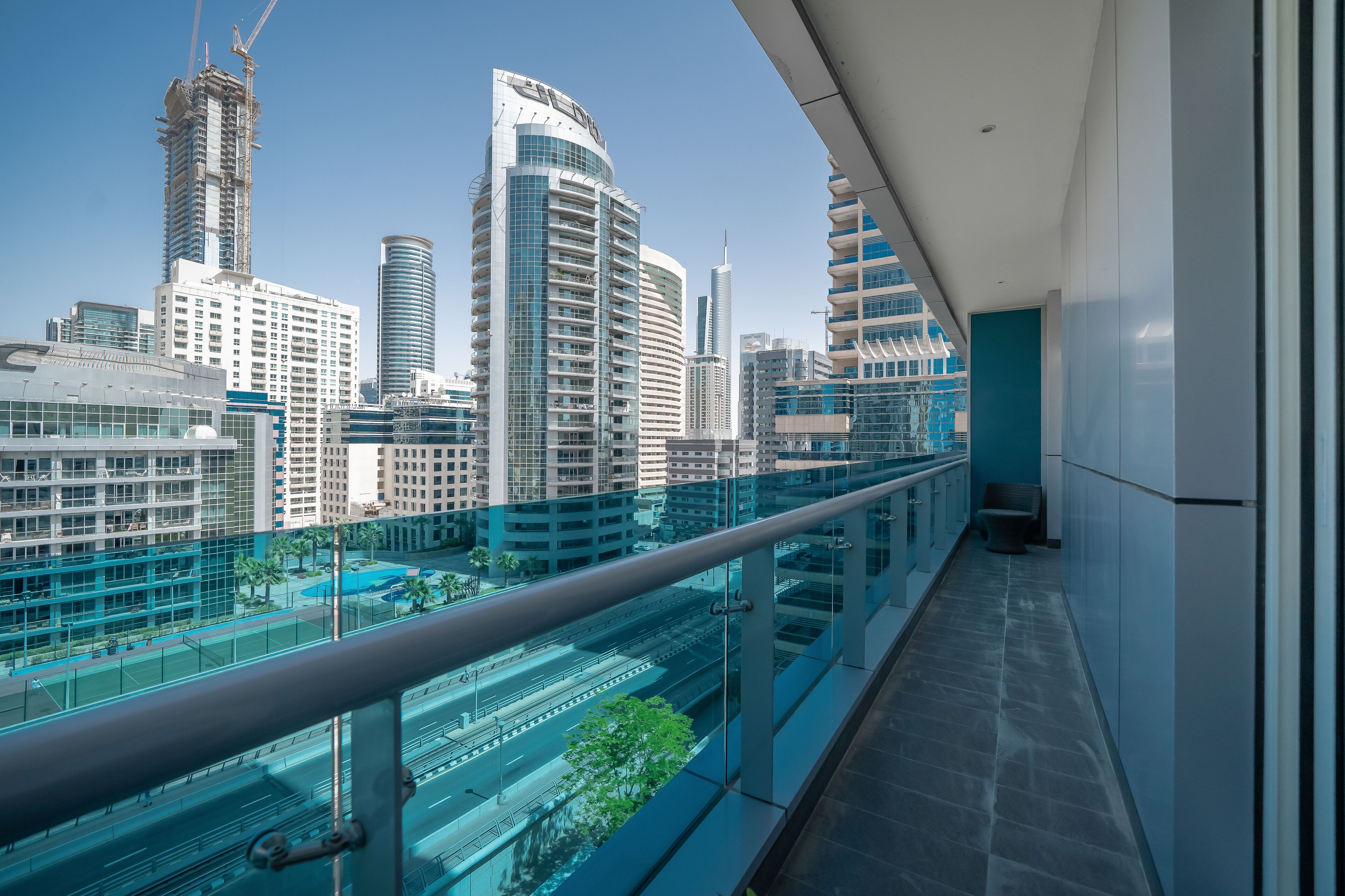 Un bâtiment moderne doté d’une façade en verre et d’un balcon donnant sur un paysage urbain.