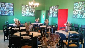 A restaurant with round tables, chairs, and wall art. - Road House GO 118 Motorcycle Hotel (Alto Paraíso de Goiás)