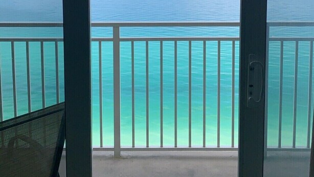 Uma varanda com vista para o oceano e guarda-corpo branco.