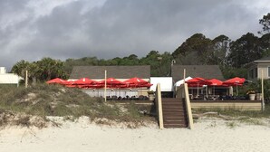 Un restaurant situé en bord de mer, avec une terrasse et des parasols rouges.
