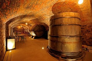 A stone-walled cellar with wooden barrels, tables, and chairs. - El Lagar de la Navazuela (El Burgo de Osma)