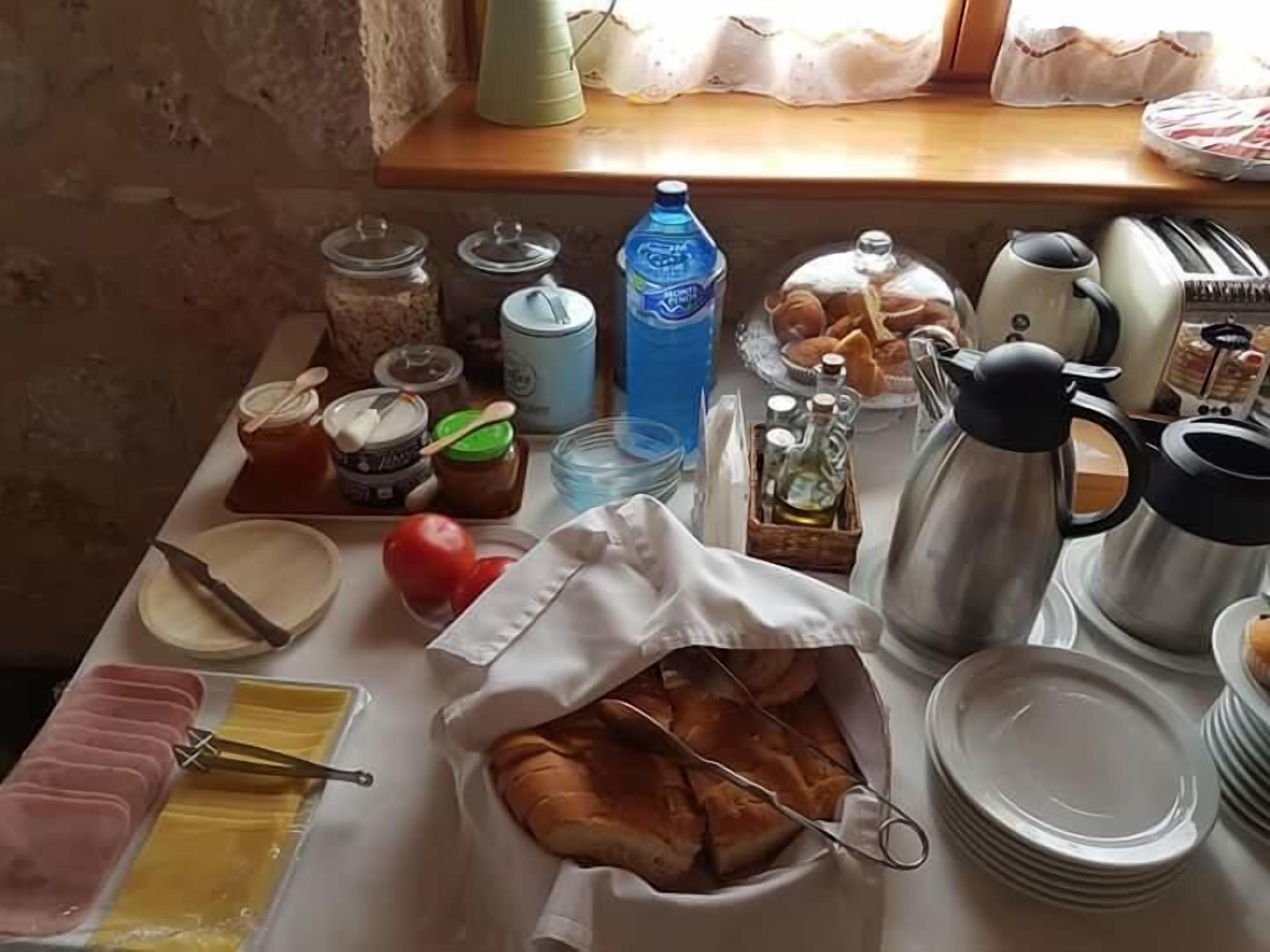 Una mesa de desayuno con diversos alimentos, condimentos y utensilios de cocina.
