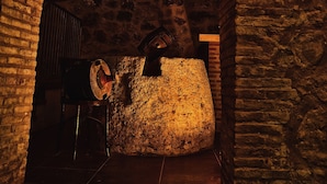 Una habitación con paredes de piedra, un barril de madera y un barril de metal.