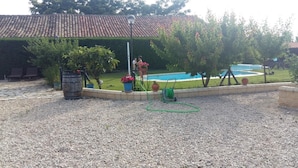 Un patio trasero con piscina, pérgola y un camino de piedra.