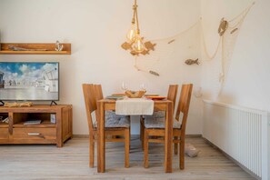 Uma sala de jantar com mesa de madeira, cadeiras e um lustre.