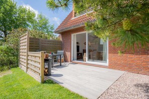 A house with a patio, a wooden fence, and a brick exterior. - Apartment 1 (ID 157), Germany (Sankt Peter-Ording)
