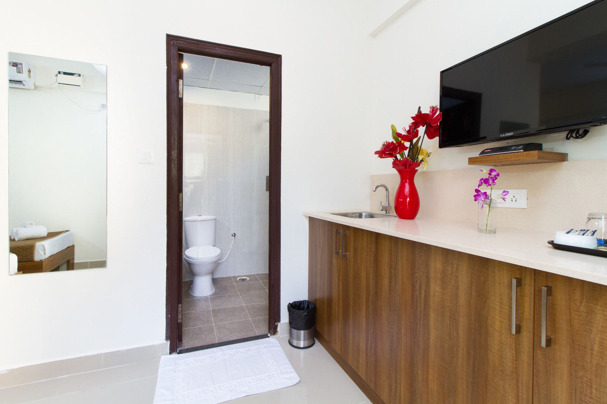 A modern bathroom with a toilet, sink, and a mounted TV.