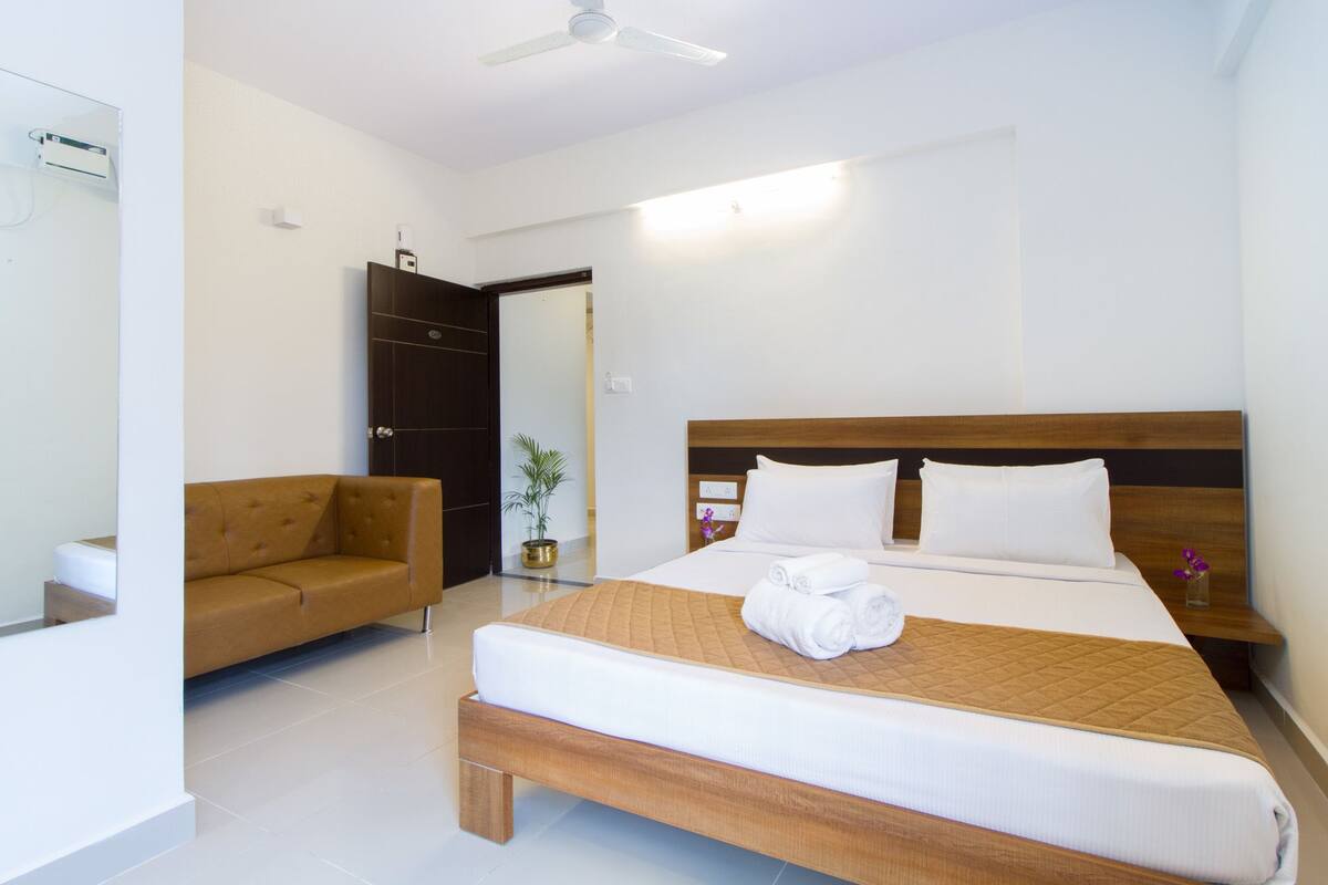 Ein Hotelzimmer mit Bett, Sofa, Topfpflanze und Deckenventilator.