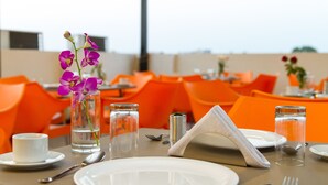 A dining table set with plates, cutlery, a vase with purple flowers, and glasses of water.