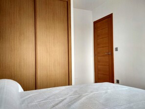 Un dormitorio con una cama, un armario de madera y una puerta.
