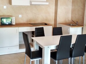 Una cocina compacta con microondas, un lavabo y una zona de comedor con sillas.