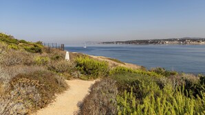 A coastal path with a white umbrella, leading to a beach with a sailboat in the distance. - Villa Hippocampe (Six-Fours-les-Plages)