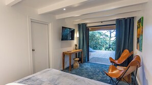 A hotel room with a bed, a desk, a chair, a TV, and a view of the outdoors. - Villa Hippocampe (Six-Fours-les-Plages)