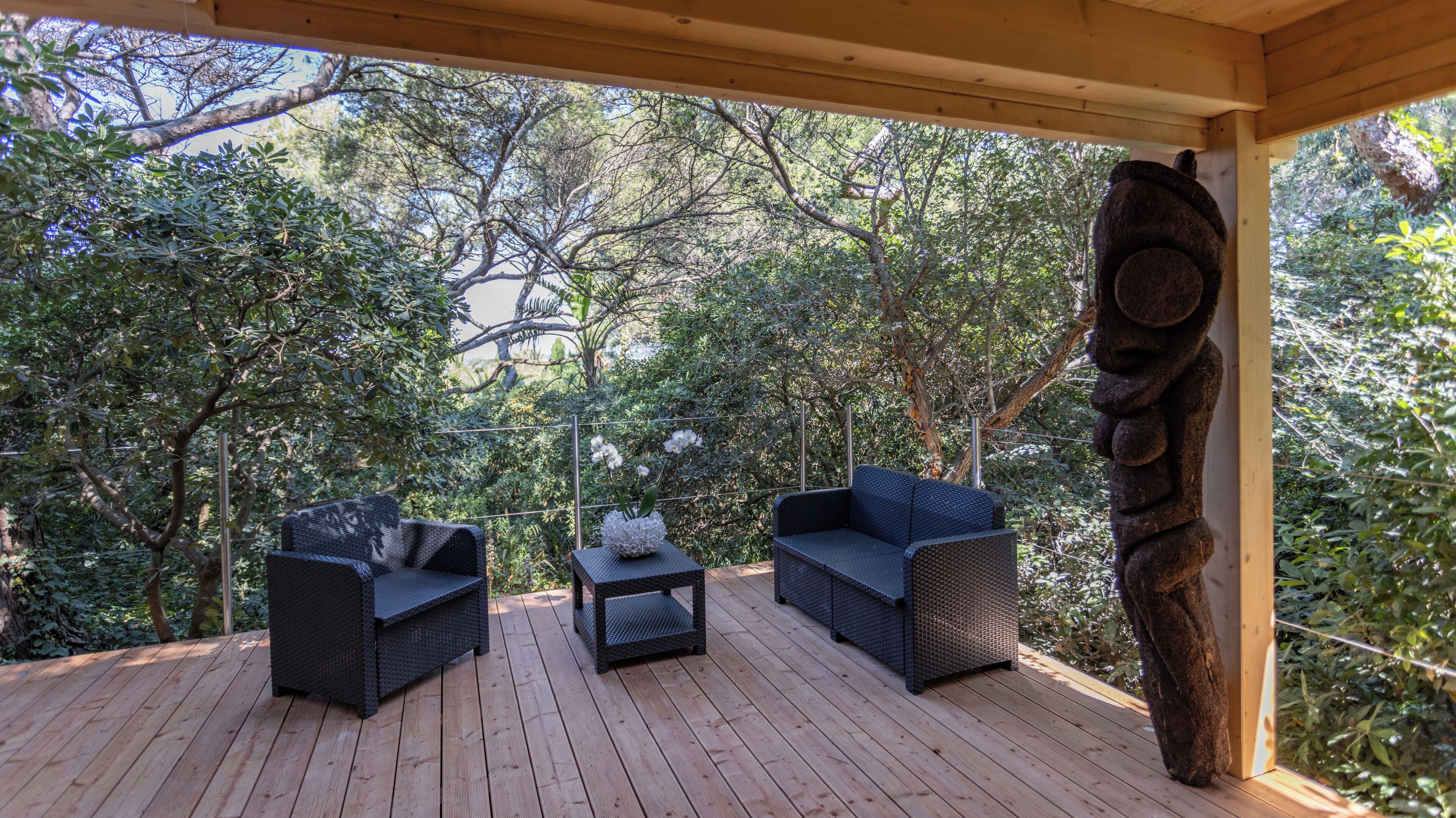Una terrazza esterna con mobili in vimini e una scultura decorativa in pietra.