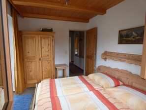 A bedroom with a wooden bed, a wardrobe, a small bedside table, and a painting on the wall. - Apartment Römerweg - House Römerweg (Strobl)