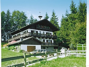 A multi-story building with balconies, a car parked in front, and a wooden fence. - Apartment Römerweg - House Römerweg (Strobl)