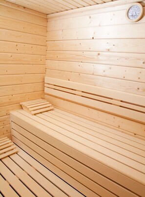 Eine Sauna mit Holzbänken und einem an der Wand befestigten Thermometer.