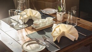 A dining table set with plates, cutlery, glasses, and napkins, with a brick wall and radiator in the background. - Schlosshotel Bergzaberner Hof (Bad Bergzabern)
