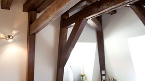 A bedroom with a large bed, wooden beams, a bedside table, and a nightstand. - Schlosshotel Bergzaberner Hof (Bad Bergzabern)