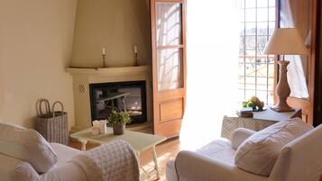 Un salón acogedor con chimenea, asientos cómodos y una mesa con lámpara.