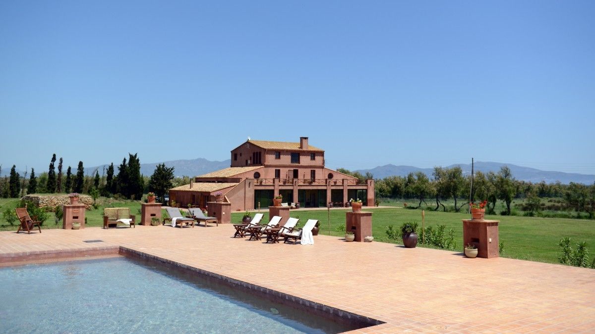 A large building with a swimming pool, outdoor seating, and a well-maintained lawn.