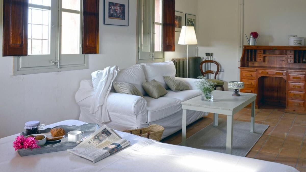 A cozy room with a white sofa, a small table with a lamp, and a wooden cabinet.