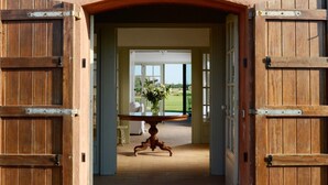 An open wooden door leading to a room with a table and a vase of flowers. - Mas del Mar (Sant Pere Pescador)