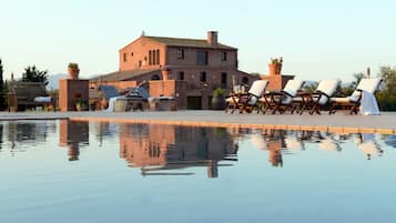 Een seizoensgebonden buitenzwembad en ligstoelen