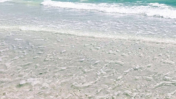Una playa con aguas turquesas cristalinas y arena blanca.