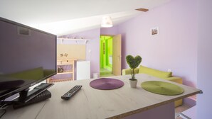 Una cocina moderna con una televisión de pantalla plana, un control remoto y una pequeña isla con una planta en maceta.