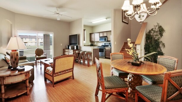 A spacious living room with a dining area, kitchen, and a staircase leading to another level. - Regal Palms Spa & Resort (Davenport)