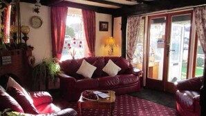 A cozy living room with a red leather sofa, a coffee table, and a patterned rug. - The Sunningdale (Skegness)