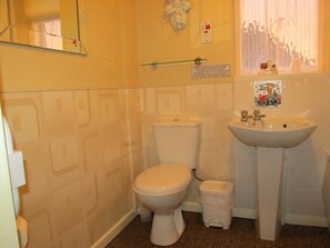 A bathroom with a toilet, sink, and a towel rack. - The Sunningdale (Skegness)