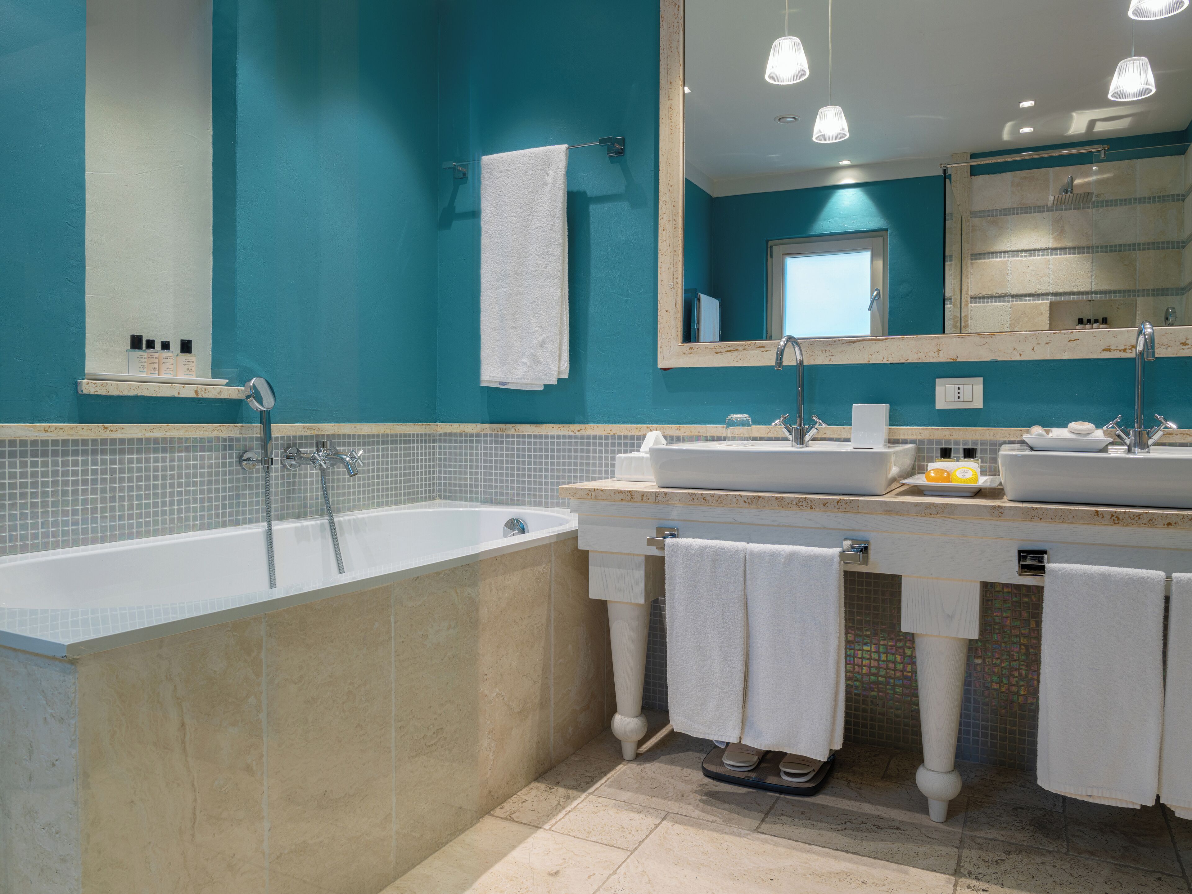 A modern bathroom with a freestanding bathtub, two sinks, and a large mirror.