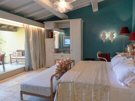 Un dormitorio con cama, escritorio, silla, armario y un ventanal con cortinas.