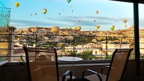 En balkon med udsigt over et bjerglandskab og varmluftsballoner.