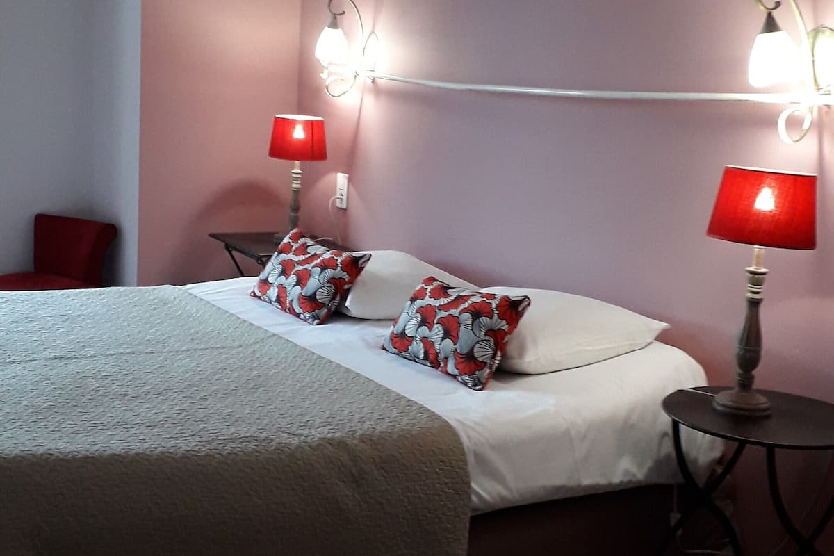 A bedroom with a bed, two bedside lamps, and a red chair.