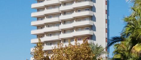 A tall, multi-story hotel with balconies and a clear sky.