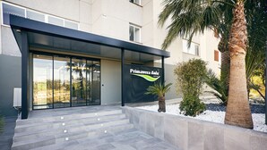 Um edifício com entrada moderna, degraus que levam a uma porta de vidro e uma placa com a inscrição "Primavera Leix".