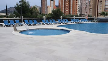 Een buitenzwembad, parasols bij het zwembad en ligstoelen