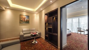 Hotelkamer met een bank, een bijzettafeltje met bloemen, een boekenkast en een bed met uitzicht op het omliggende landschap.
