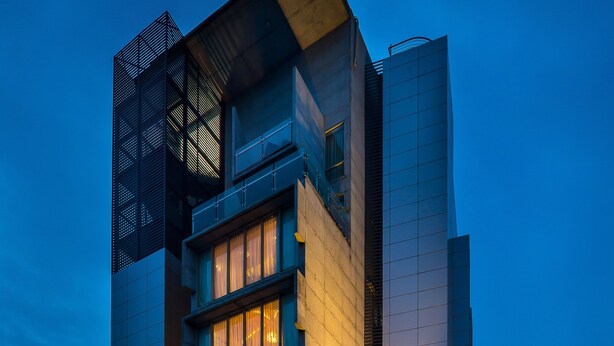 Een modern gebouw met meerdere verdiepingen, grote ramen en een opvallende ingang met een trap.