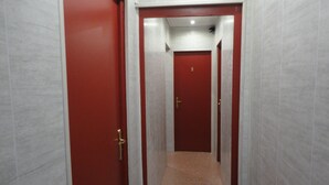 Un couloir avec des portes rouges et des murs blancs.