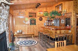 Un intérieur en bois avec un bar, des sièges et un jeu de fléchettes.