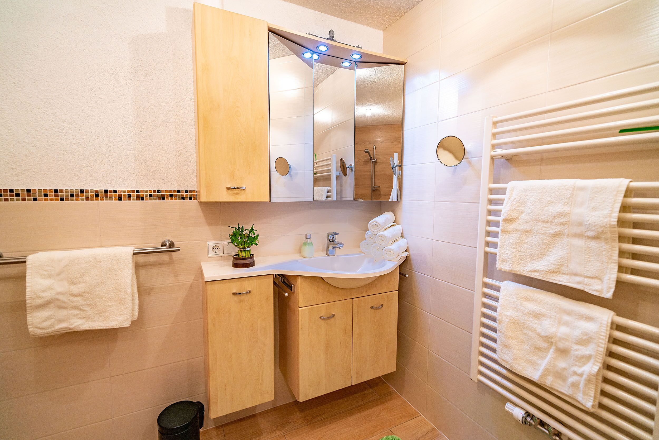 Un baño moderno con tocador de madera, un espejo grande, un perchero y un calentador empotrado.